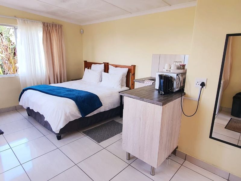A functional bedroom featuring tiled flooring, built-in cabinetry, and a compact kitchenette area with a laminate countertop.
