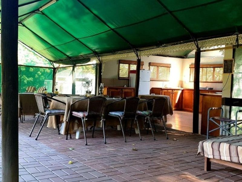 Spacious covered outdoor patio featuring paved flooring, timber support posts, and an integrated kitchen area with cabinetry and sink, ideal for outdoor entertaining.