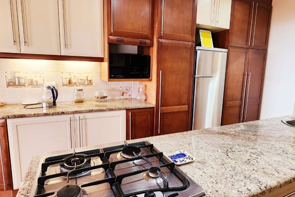 A functional kitchen featuring granite countertops, a gas cooktop, built-in cabinetry, and a stainless steel sink with a tiled backsplash.