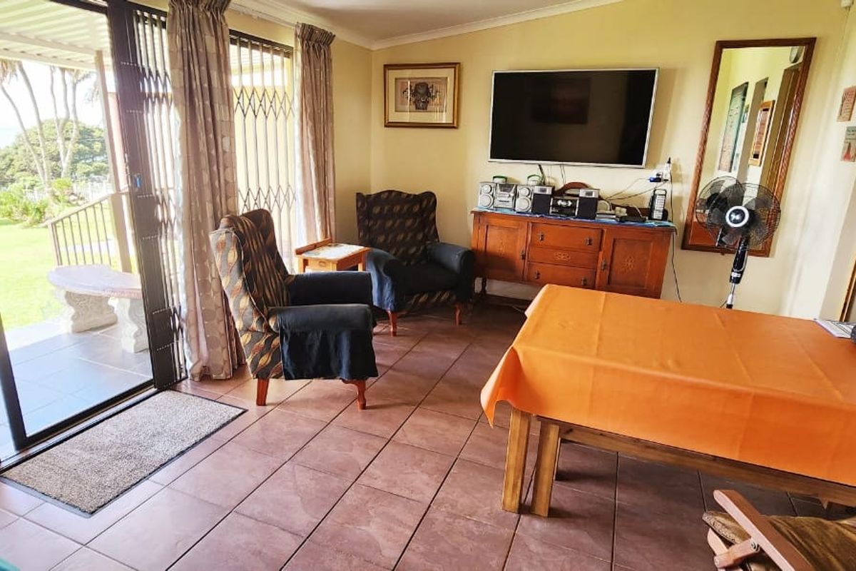 A living room featuring tiled flooring and large sliding glass doors that provide direct access to the outdoor patio and garden area.