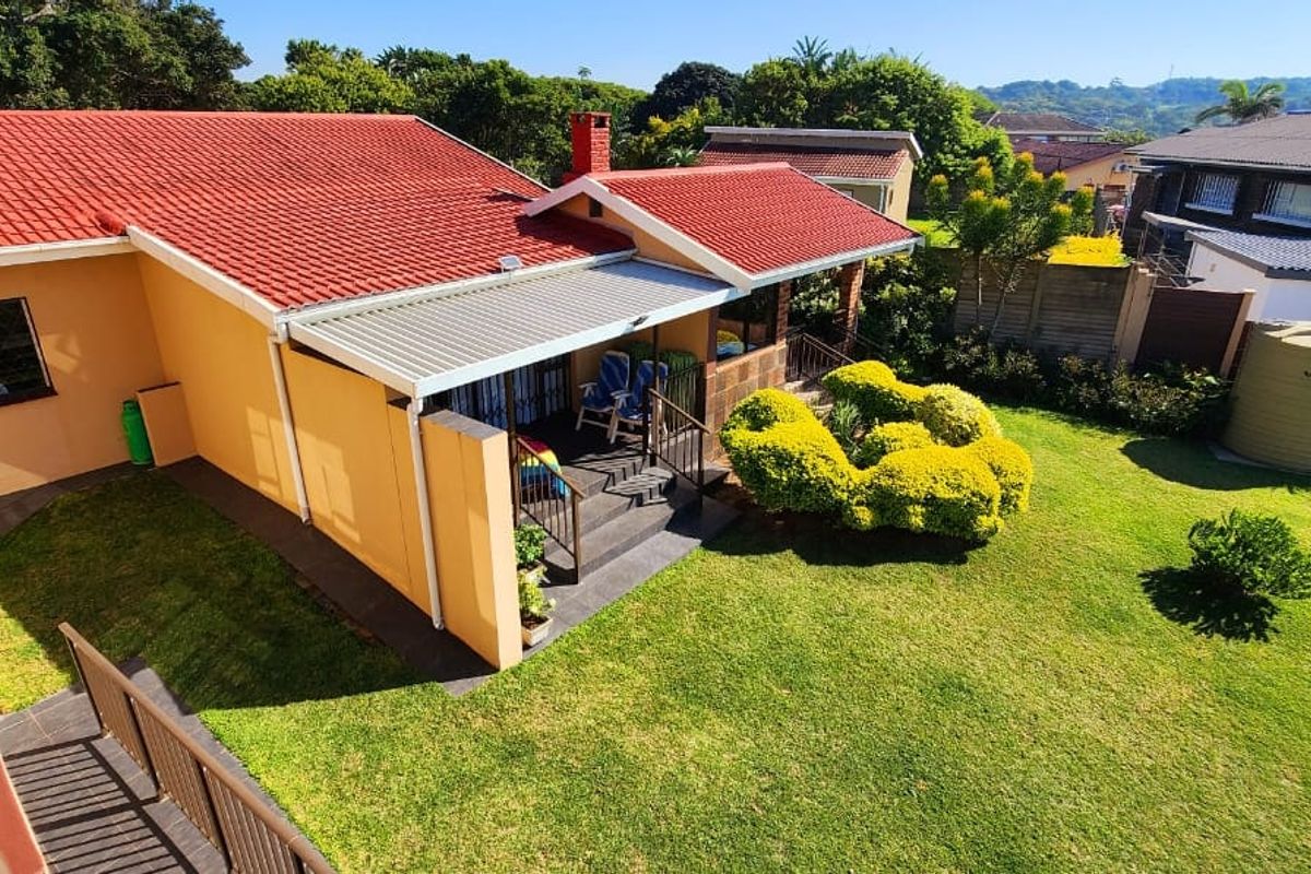 Aerial view of the property featuring a tiled roof, covered patio area, and a well-maintained garden with a water storage tank.