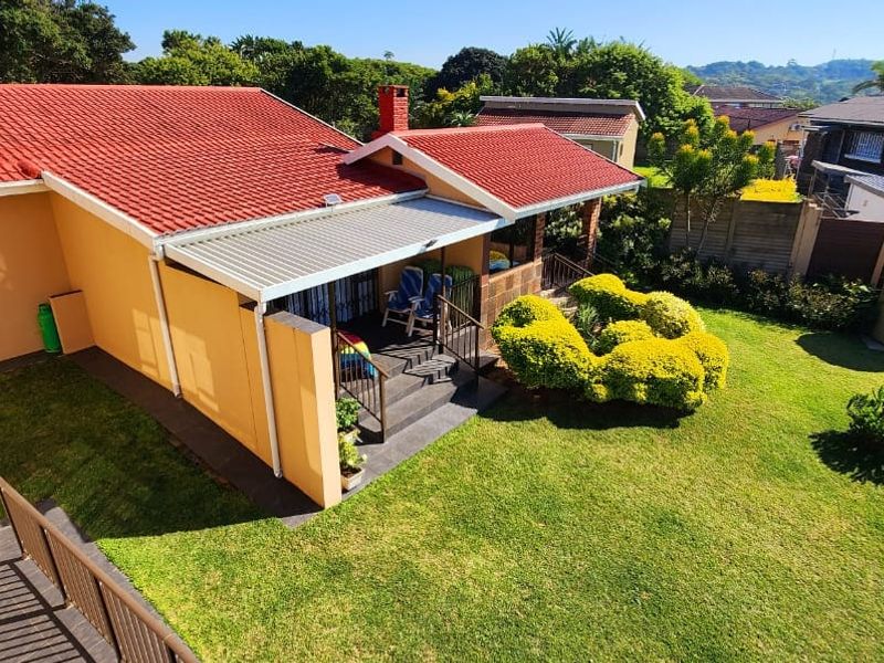 Aerial view of the property featuring a tiled roof, covered patio area, and a well-maintained garden with a water storage tank.