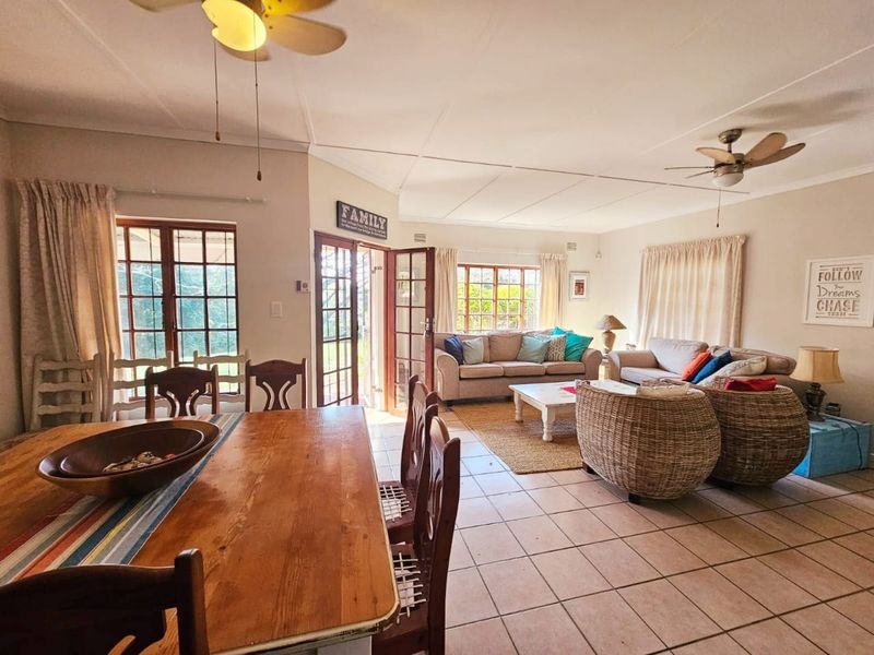 Spacious open-plan living and dining area featuring tiled flooring, ceiling fans, and multiple timber-framed glass doors providing access to the exterior.