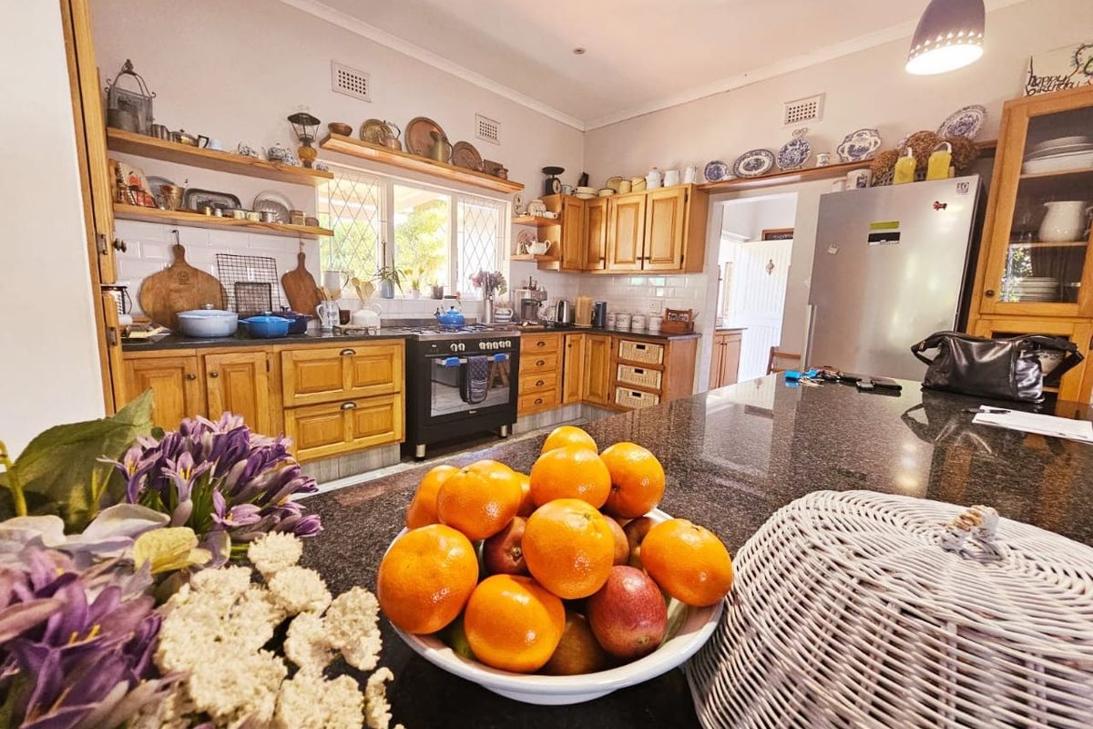 A warm, country-style kitchen featuring wooden cabinetry, granite countertops, subway tile backsplash, and open shelving, creating a functional and inviting culinary space.