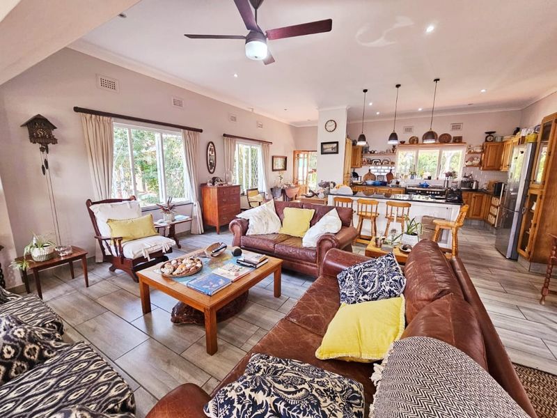 Spacious open-plan living and kitchen area featuring tiled flooring, a central kitchen island with breakfast bar, and integrated lighting throughout.