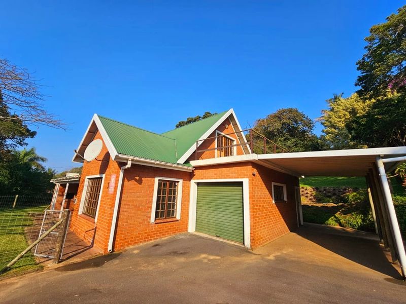 Front exterior view of a brick house featuring a green metal roof, integrated garage, and a covered carport area.