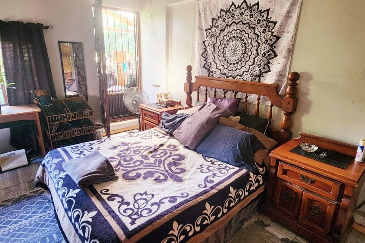 A bedroom featuring tiled flooring and security bars on the windows, providing a functional space with natural light.