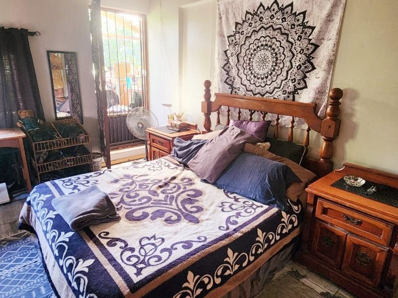 A bedroom featuring tiled flooring and security bars on the windows, providing a functional space with natural light.