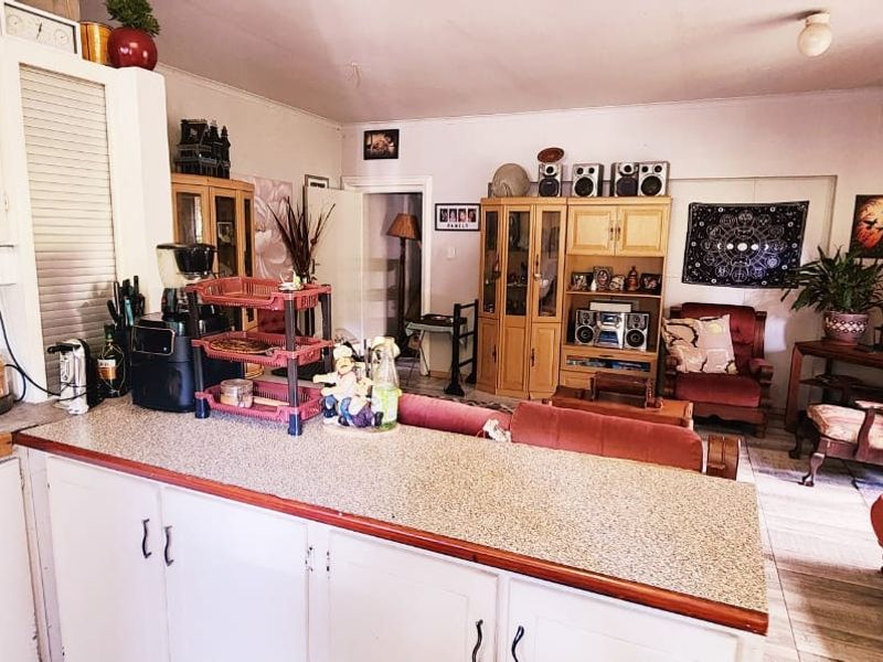 Open plan kitchen and living area featuring laminate countertops, built-in cabinetry, and tiled flooring, offering a functional layout with potential for modernization.