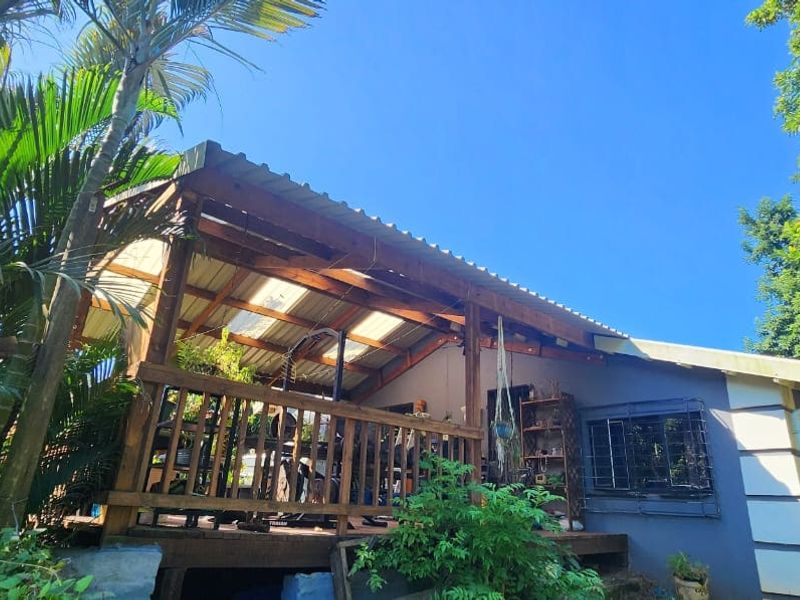A covered timber patio area featuring a corrugated roof and balustrade, providing an outdoor living space overlooking the garden.