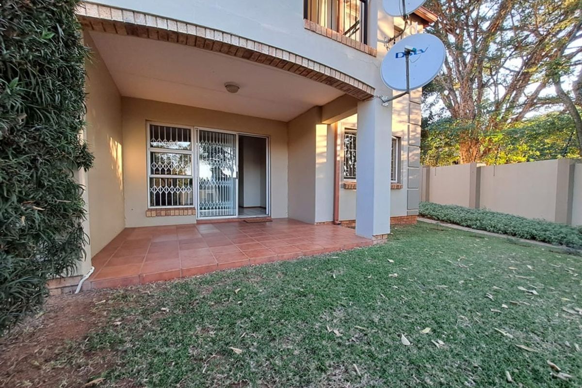 A ground floor apartment featuring a tiled patio area, sliding door access with security gate, and a private garden space.