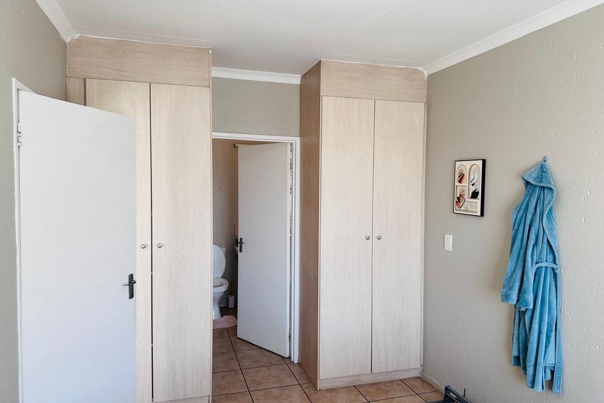 Bedroom featuring light wood-finish built-in cupboards, tiled flooring, and direct access to an en-suite bathroom.