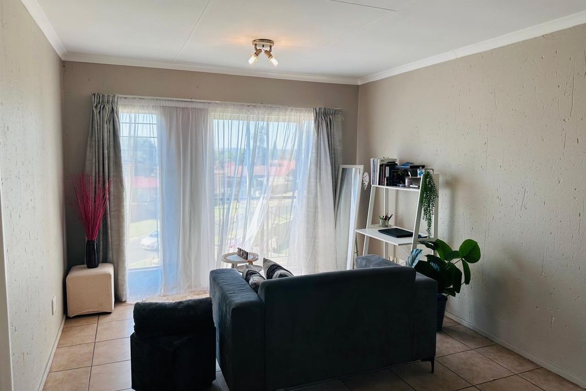 A living room featuring tiled flooring, coved ceilings, and a large sliding glass door providing access to a balcony.