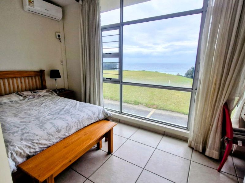 A bedroom featuring tiled flooring, an air conditioning unit, and large windows offering scenic coastal views.