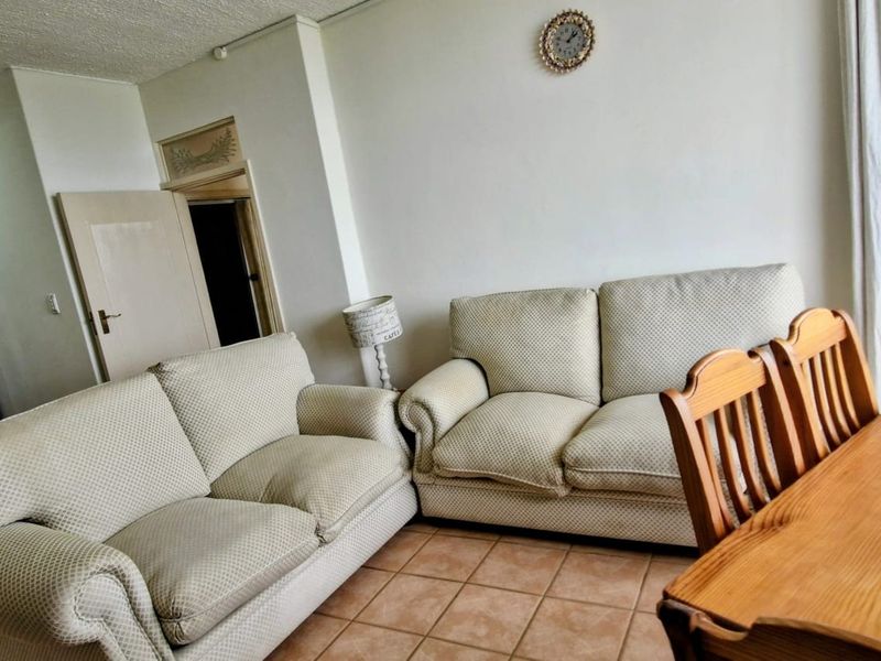 A living and dining area featuring tiled flooring and neutral walls, providing a functional space for relaxation and meals.