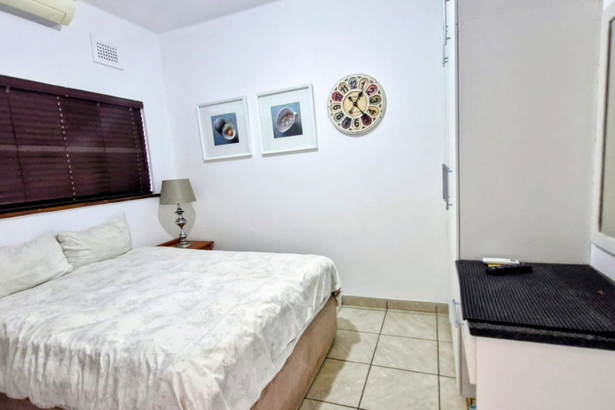 A functional bedroom featuring tiled flooring, a built-in wardrobe, venetian blinds, and an integrated air conditioning unit.