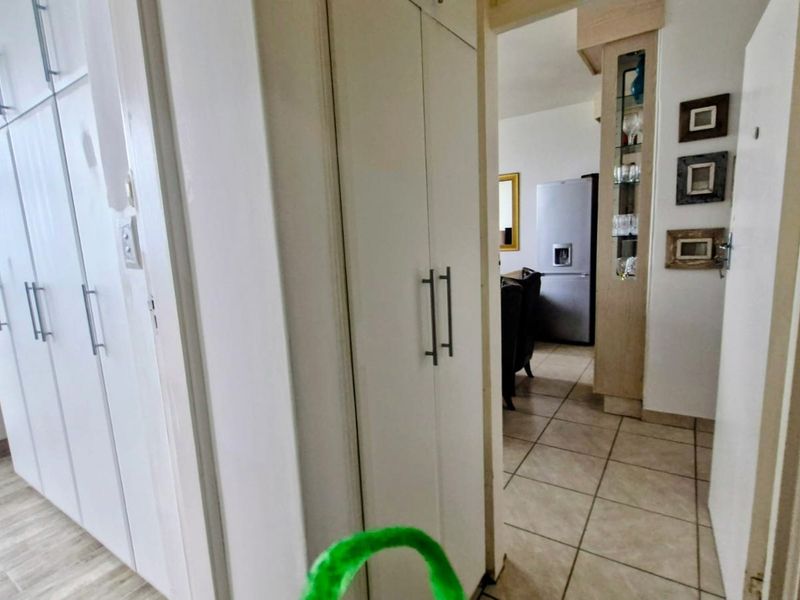 A functional hallway featuring extensive built-in cupboard storage and tiled flooring, providing a clean transition between the apartment living areas.