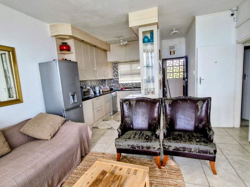Open plan living and kitchen area featuring built-in cabinetry, mosaic backsplash, and tiled flooring, providing a functional layout for modern apartment living.