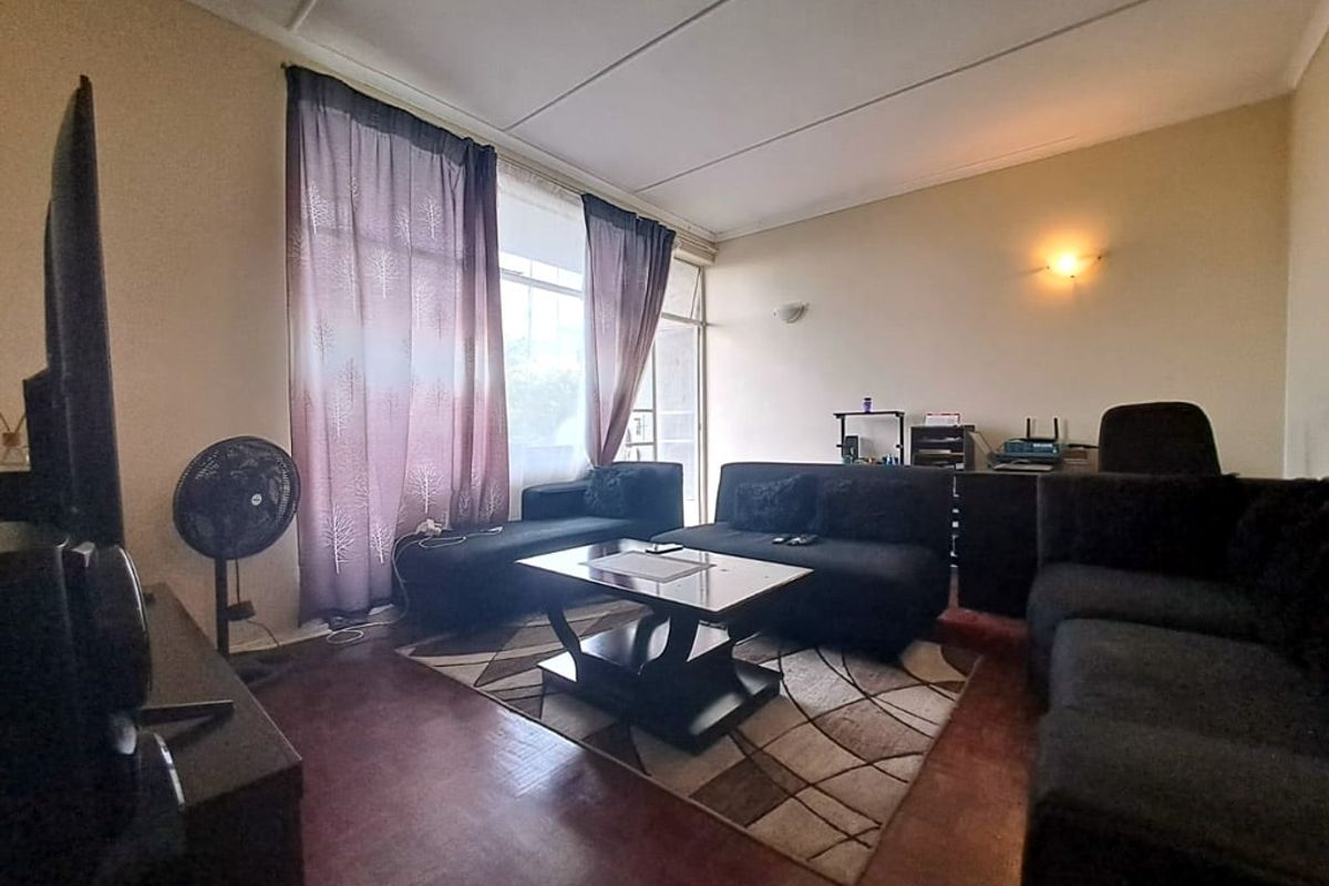 A living room featuring parquet flooring and a large sliding glass door providing natural light and access to the exterior.