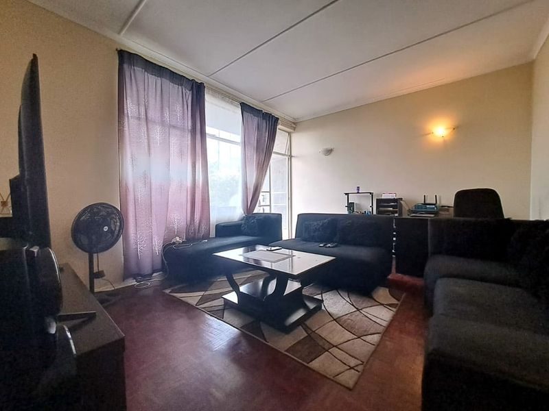 A living room featuring parquet flooring and a large sliding glass door providing natural light and access to the exterior.