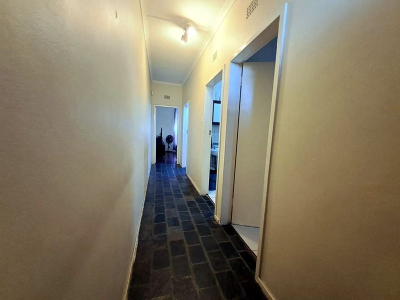 A functional hallway featuring dark tiled flooring and access to multiple rooms, providing a central circulation space within the apartment.