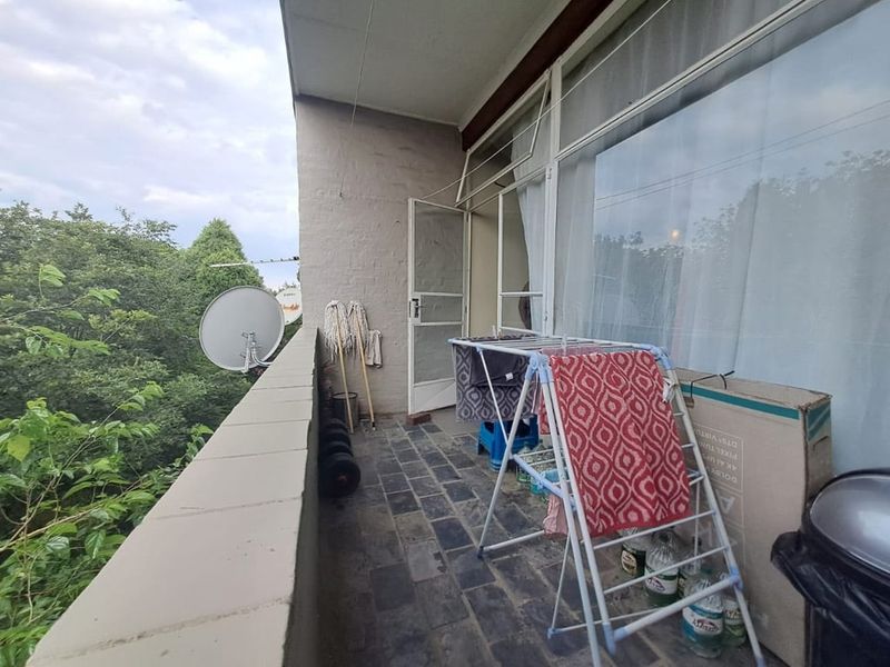 A functional balcony space featuring stone tile flooring and a parapet wall, offering an outdoor area accessible from the main living space.