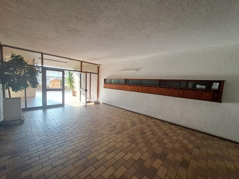 Spacious apartment building entrance lobby featuring brick flooring, textured walls, and a wall-mounted bank of wooden mailboxes.
