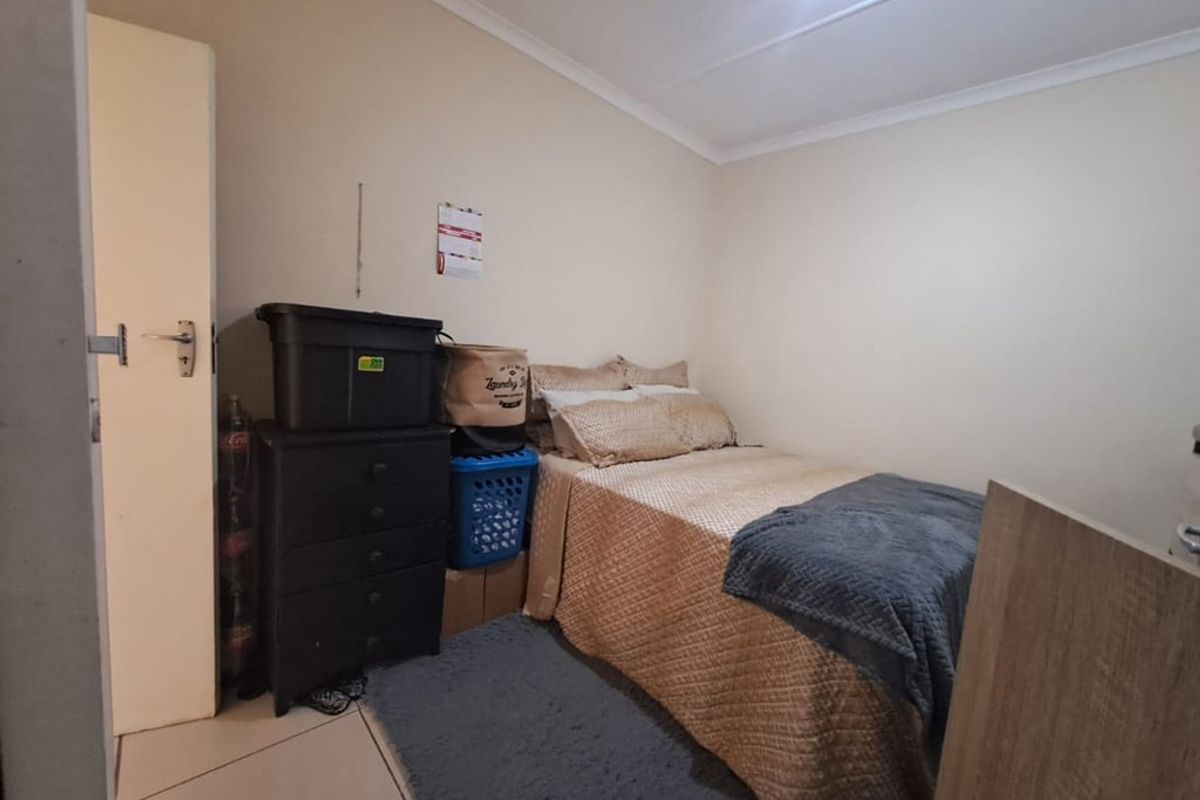 A compact bedroom featuring tiled flooring and neutral wall finishes, providing a functional space for rest.