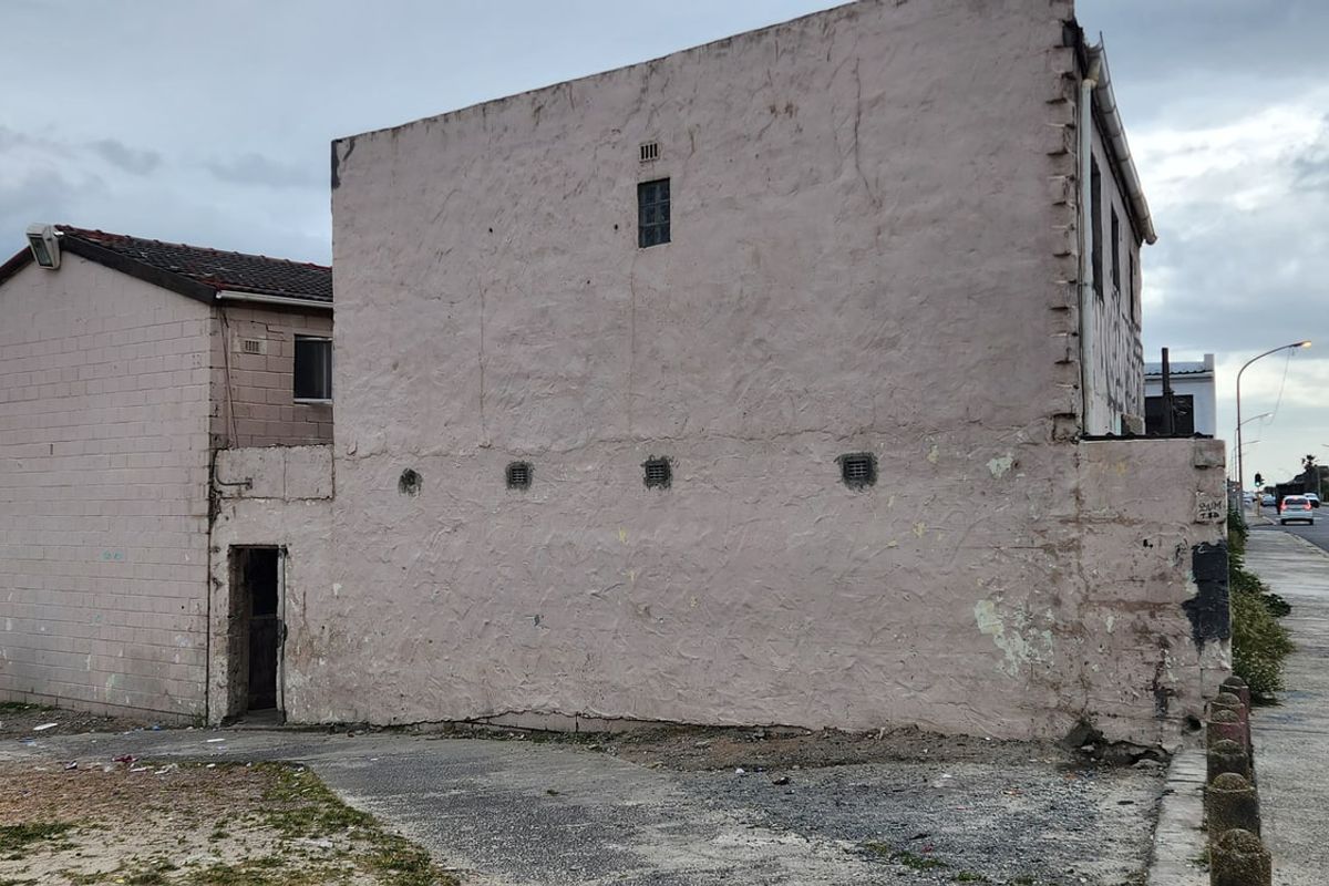 Side and front elevation of a masonry house showing significant weathering and deterioration of the exterior plaster and paint finishes.