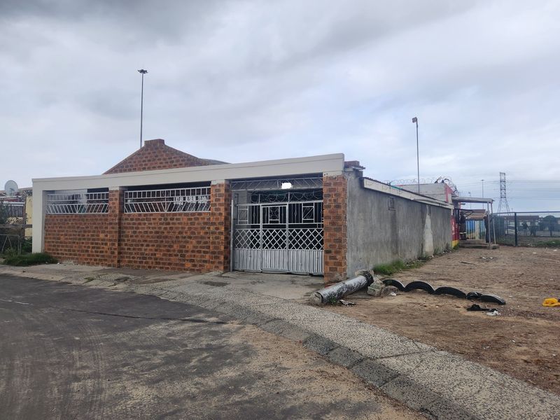 Front exterior view of a face brick property featuring security gates, burglar bars, and perimeter razor wire fencing.