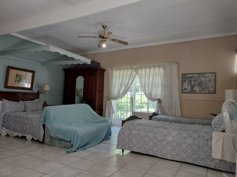 Spacious bedroom featuring tiled flooring, a ceiling fan, and direct access to the outdoors through glass-paned french doors.
