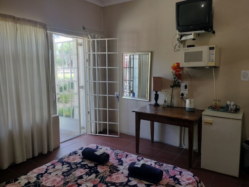 A bedroom featuring tiled flooring and direct access to an outdoor area through a glass door with a security gate.
