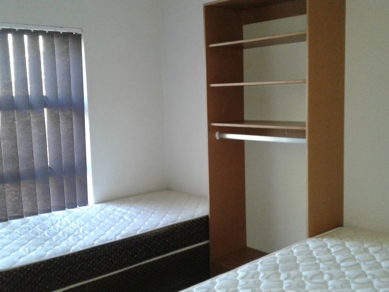 A bedroom featuring a built-in wardrobe and vertical window blinds.