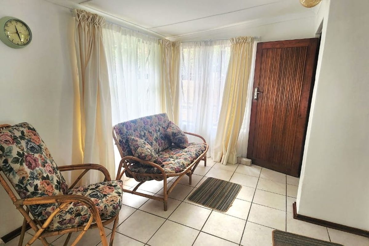 A sunlit living area featuring tiled flooring and a classic timber door, offering a neutral foundation for modern interior updates.