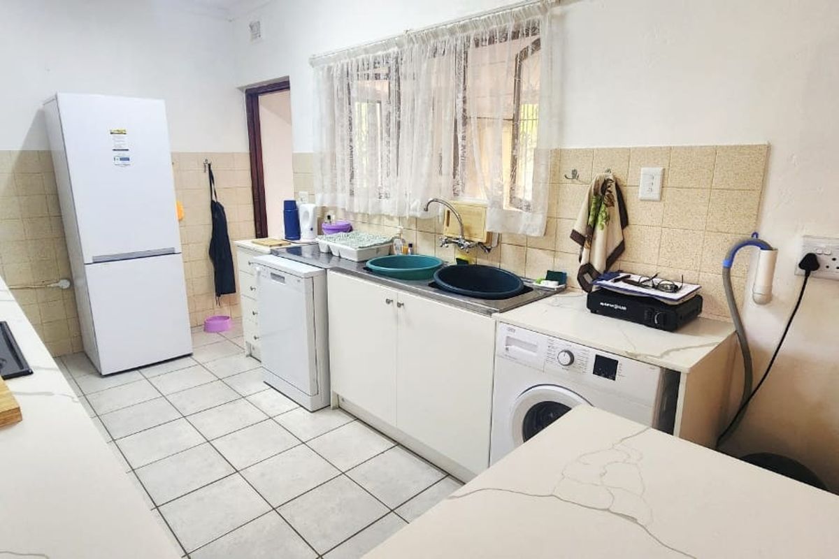 Functional kitchen featuring quartz countertops, tiled backsplash, and integrated cabinetry with space for laundry appliances.