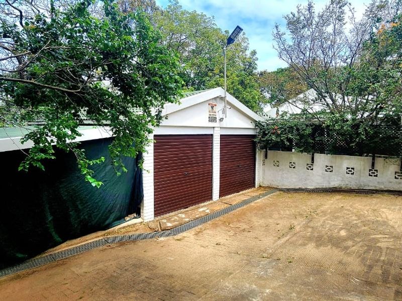 Exterior view of a double garage with a paved driveway and surrounding garden area.