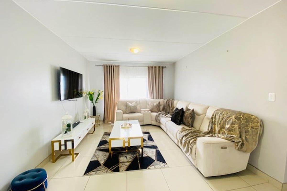 A well-maintained living room featuring neutral tiled flooring and clean wall finishes, providing a bright and comfortable space for relaxation.