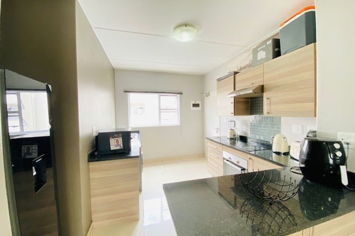 A functional kitchen featuring light wood-finish cabinetry, dark granite countertops, a built-in oven, and a tiled backsplash, offering a clean and practical workspace.