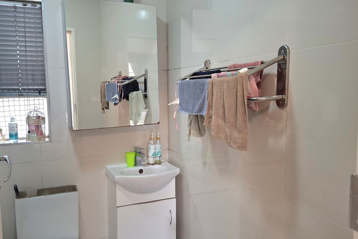 A compact bathroom featuring a wall-mounted vanity basin, mirrored medicine cabinet, toilet, and tiled wall finishes.
