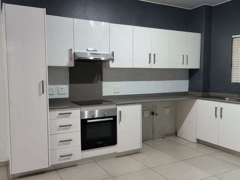 Modern kitchen featuring white cabinetry, built-in oven and hob, extractor fan, and tiled flooring. The space includes a dedicated area for an under-counter appliance.