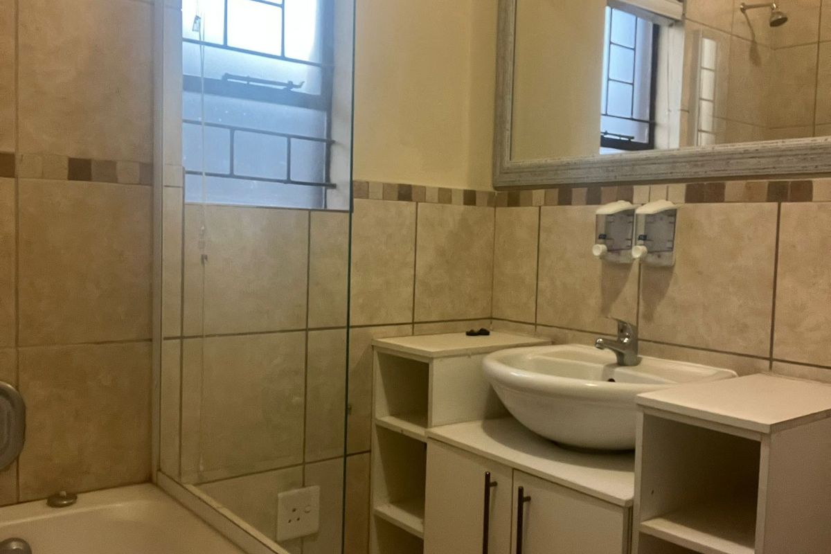 A functional bathroom featuring a vessel sink vanity, tiled walls, and a bathtub with shower fixtures.