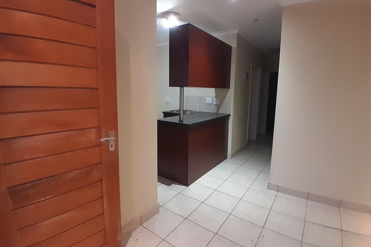 A compact kitchen area featuring dark wood cabinetry, a breakfast counter, and tiled flooring, presented in a clean, vacant state.