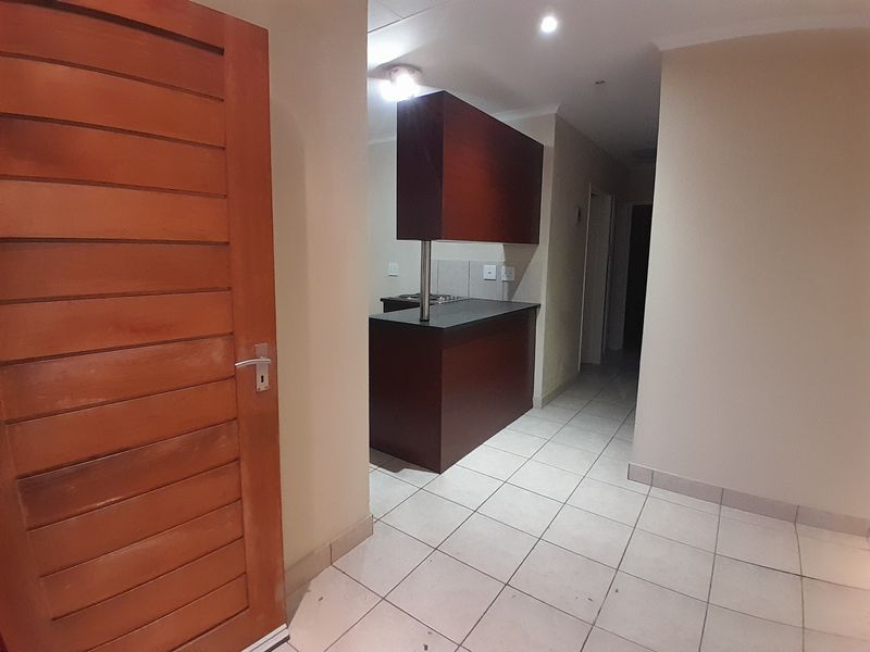 A functional kitchen area featuring dark wood cabinetry, a breakfast counter, and tiled flooring, presented in a clean, vacant state.