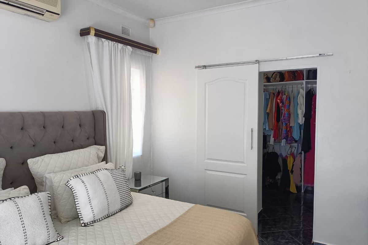 A bedroom featuring a sliding door leading to a walk-in closet, tiled flooring, and a wall-mounted air conditioning unit.