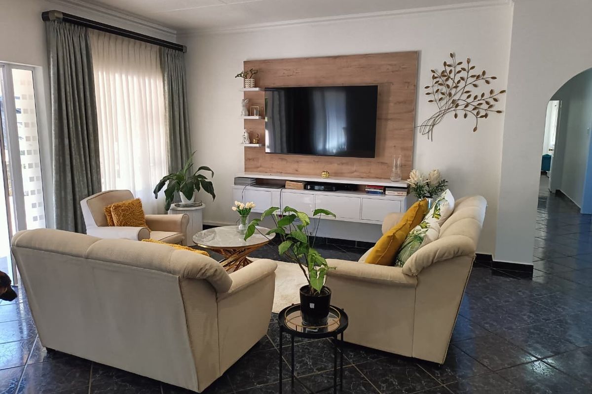 A well-maintained living room featuring a built-in media wall unit, recessed ceiling lighting, and dark tiled flooring.