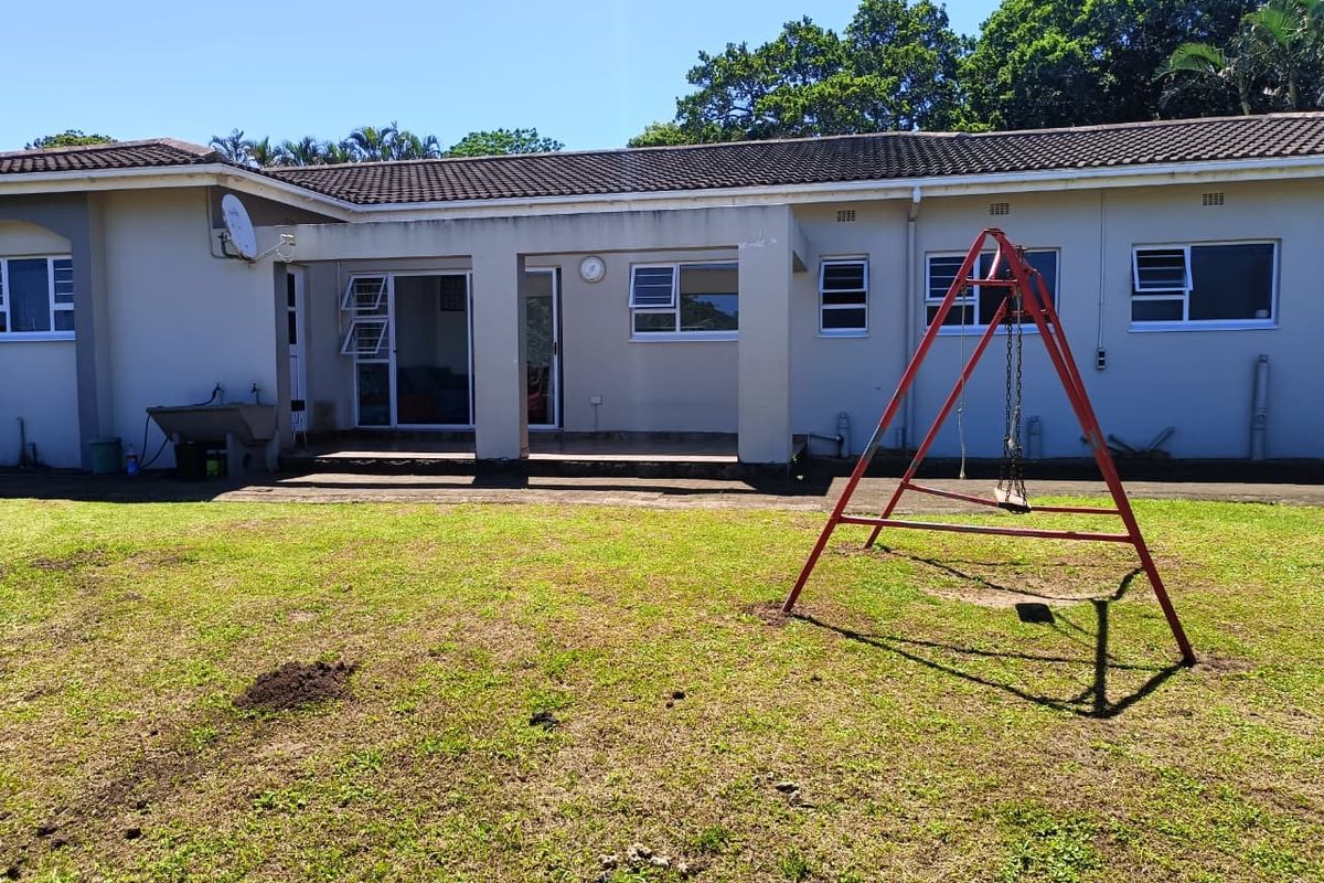 Rear view of the property featuring a covered patio area, tiled flooring, and a spacious backyard with established lawn.