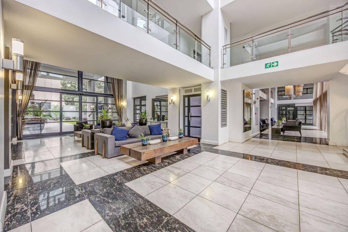 Spacious double-volume entrance lobby featuring polished marble flooring, glass balustrades, and large floor-to-ceiling windows providing ample natural light.