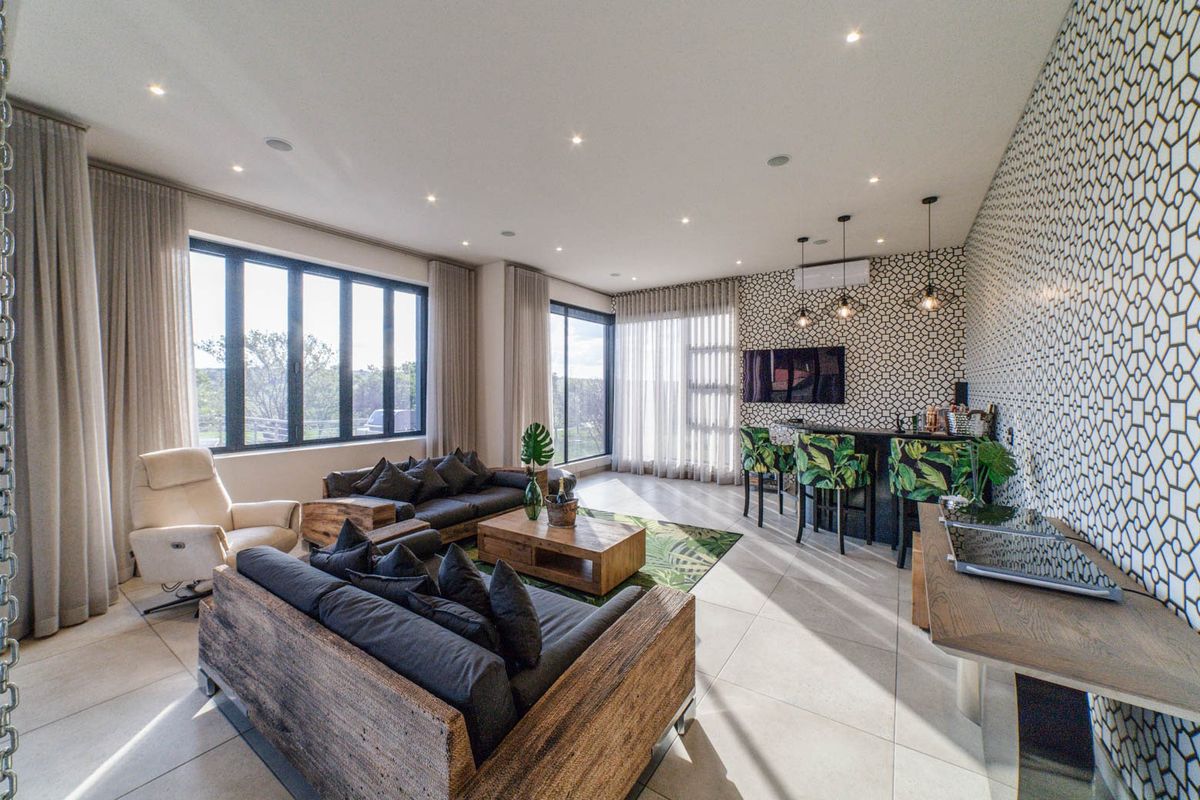 Spacious living room featuring tiled floors, recessed lighting, a built-in bar area, and large windows providing ample natural light.