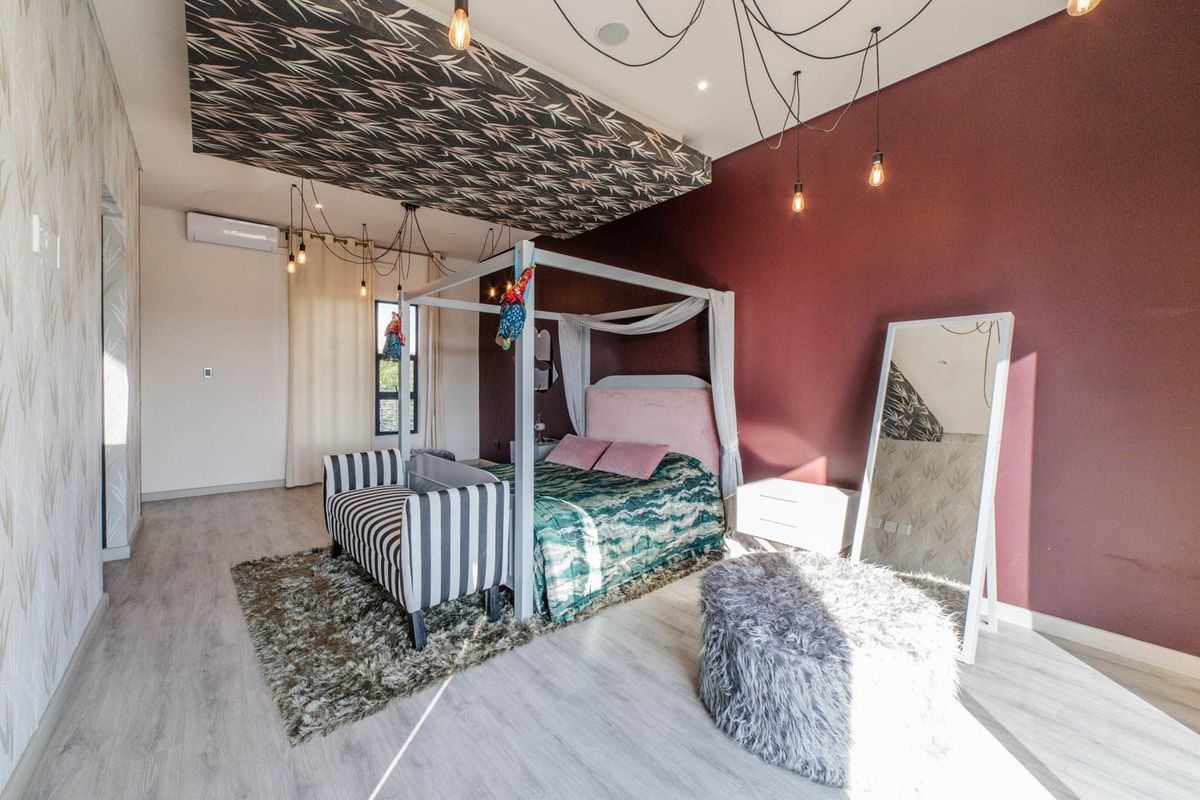 Spacious bedroom featuring a unique patterned ceiling panel, recessed lighting, split-system air conditioning, and modern laminate flooring.