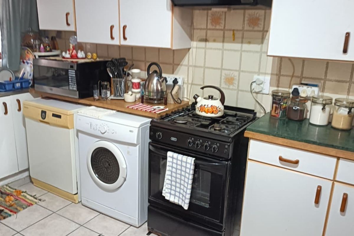 A functional kitchen featuring built-in cabinetry, a gas stove with oven, and tiled backsplash, offering a practical layout for daily meal preparation.